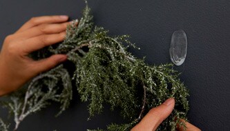 Osoba wieszająca świąteczne dekoracje na ścianie
